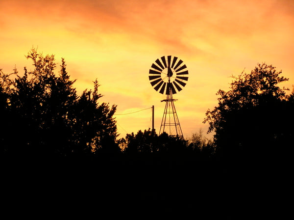 Ranch windmill silhouetted against a golden orange sunset